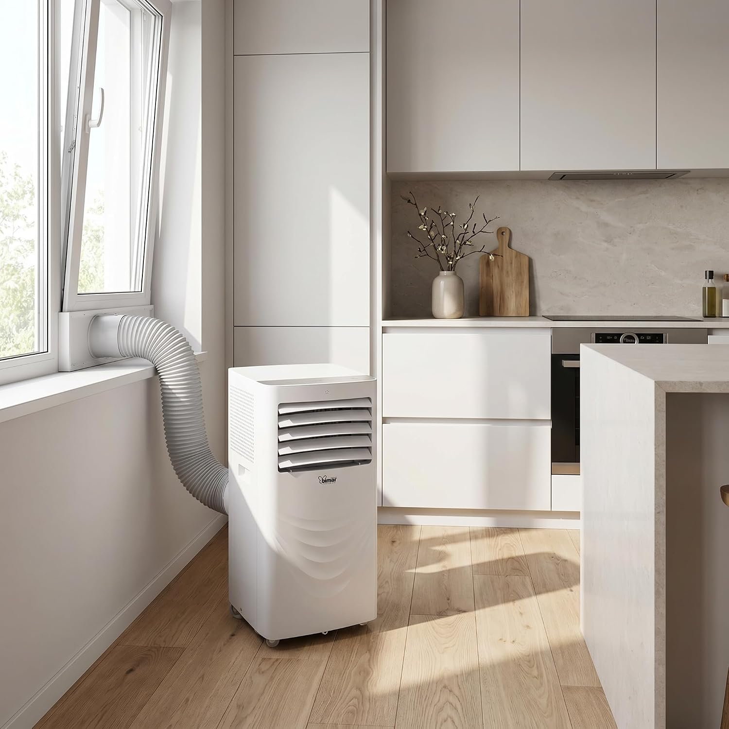 The Bimar INB-CP528 portable air conditioner placed in a modern kitchen next to a window, with the exhaust hose connected to a window kit, directing hot air outside. The unit is white and compact.