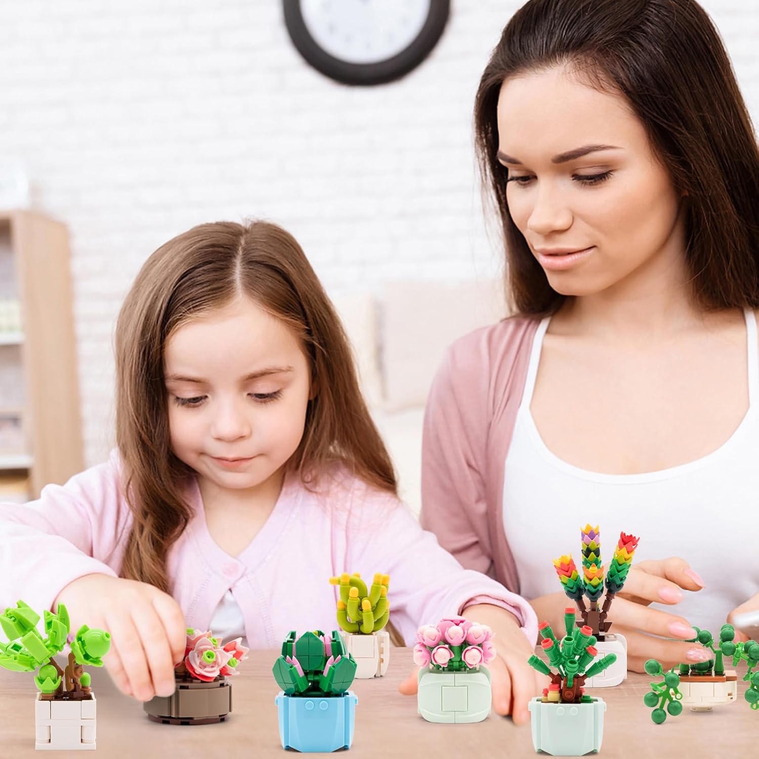 An adult and a child sitting at a table, looking at a collection of assembled succulent building block models, highlighting the product's appeal for shared activities and display.