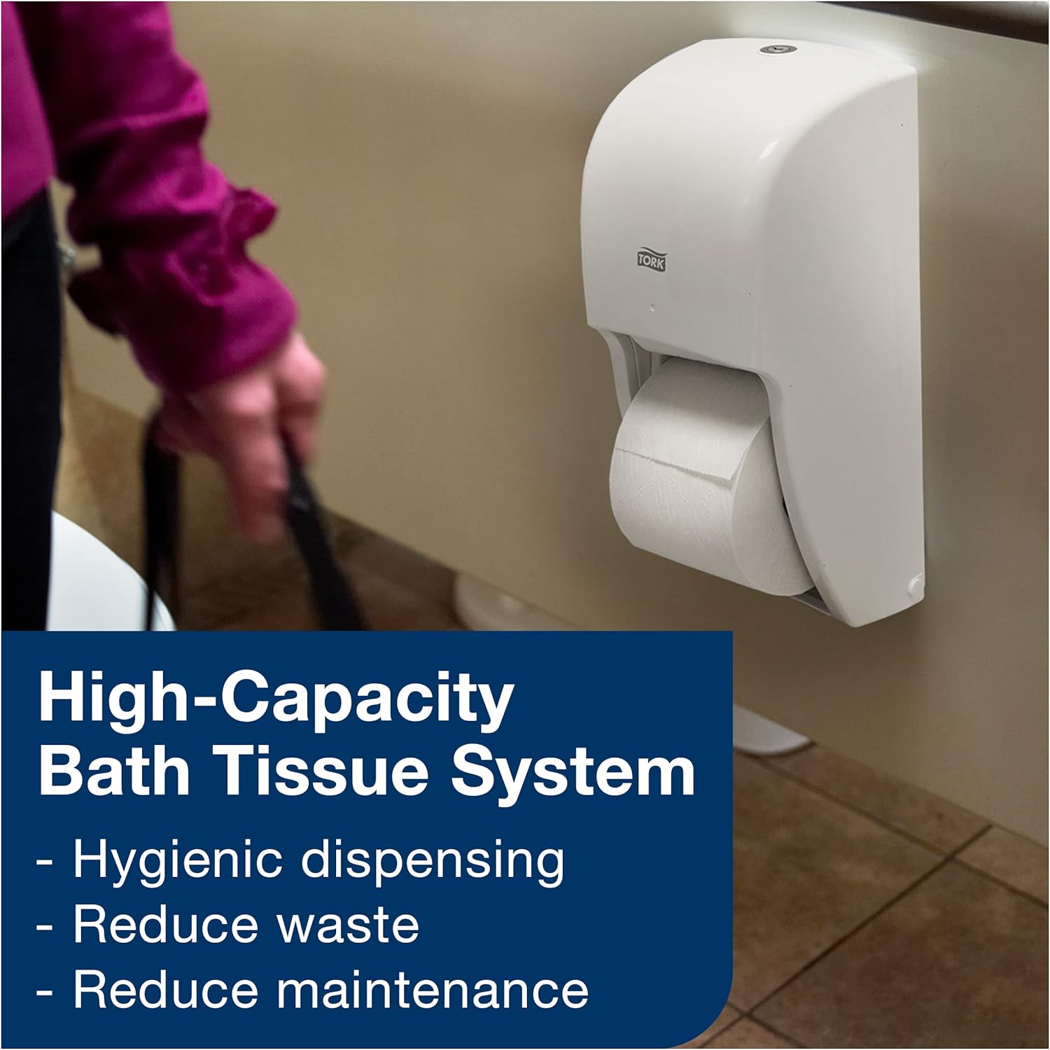 A Tork dispenser mounted on a wall in a restroom setting, highlighting its high-capacity bath tissue system benefits: hygienic dispensing, reduced waste, and reduced maintenance.