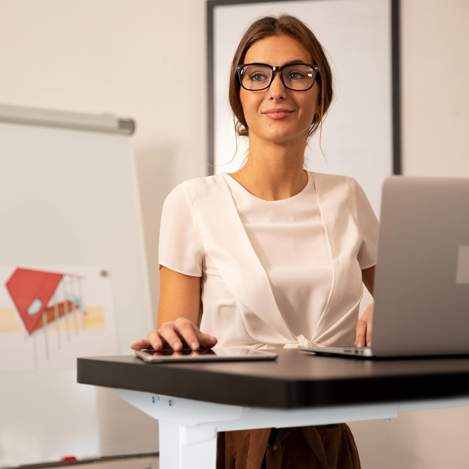 Woman standing at an electric height-adjustable desk.