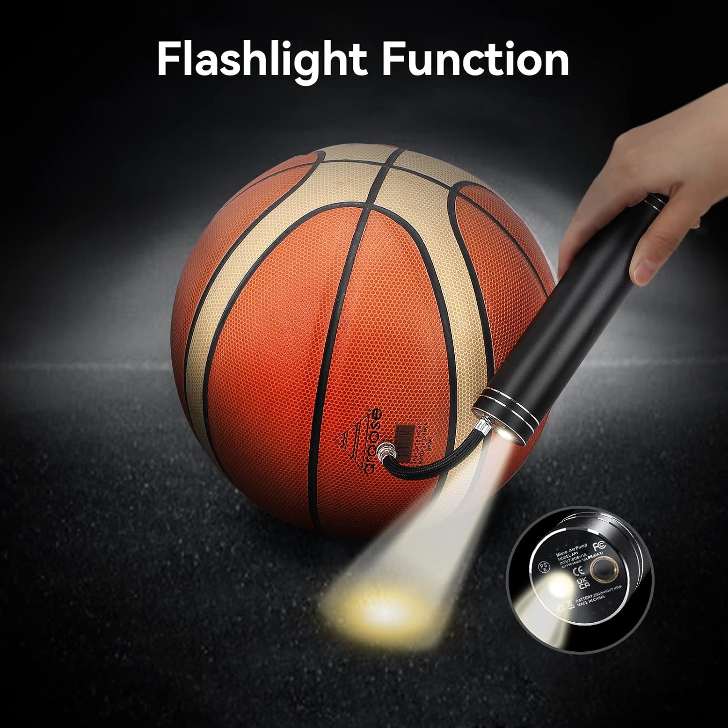 The morpilot electric ball pump being used as a flashlight, illuminating a basketball in a dark setting.
