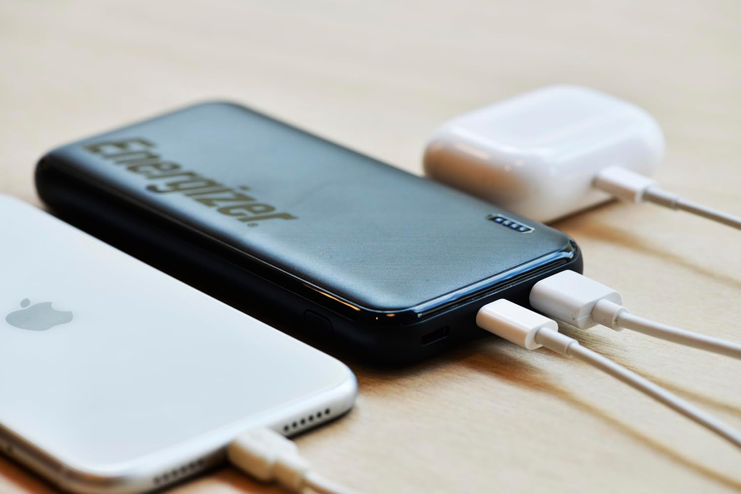 Energizer UE10055PQ power bank charging a smartphone and wireless earbuds.