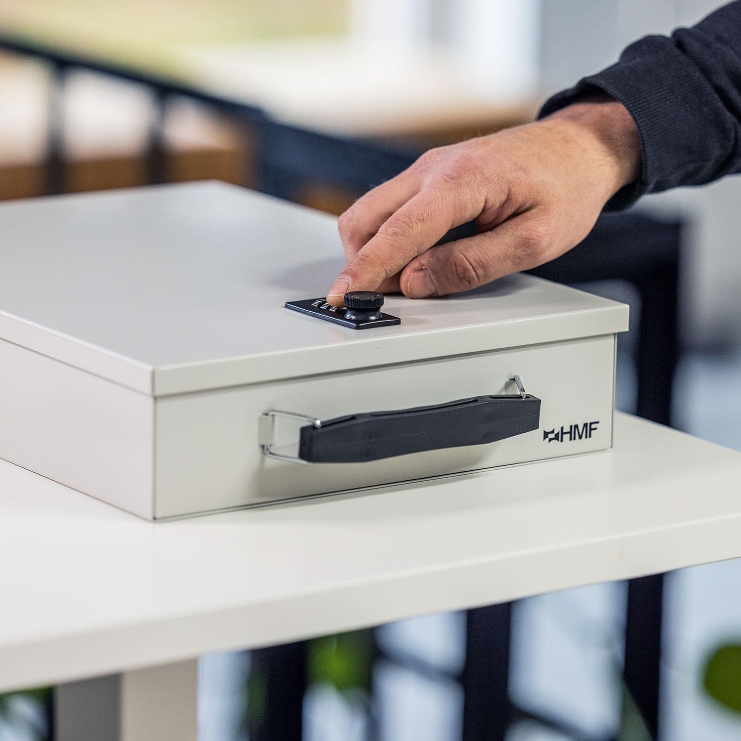 Hand operating the combination lock on the HMF document box.