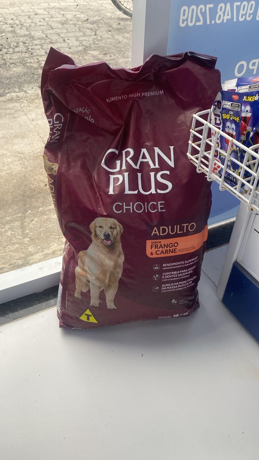 Saco de ração Granplus Choice para cães adultos, posicionado em uma prateleira com outros produtos.