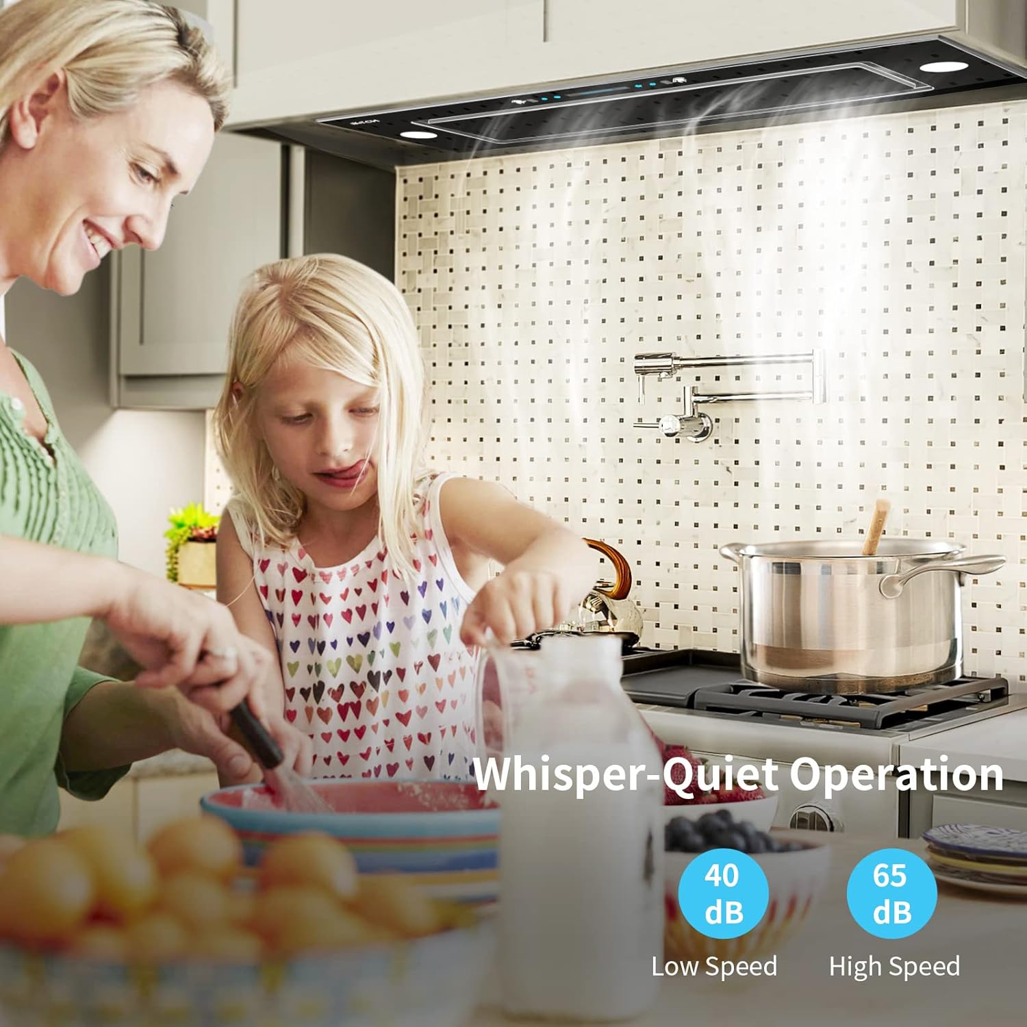 Woman and child cooking with the IKTCH range hood operating, highlighting its quiet operation (40-65 dB).