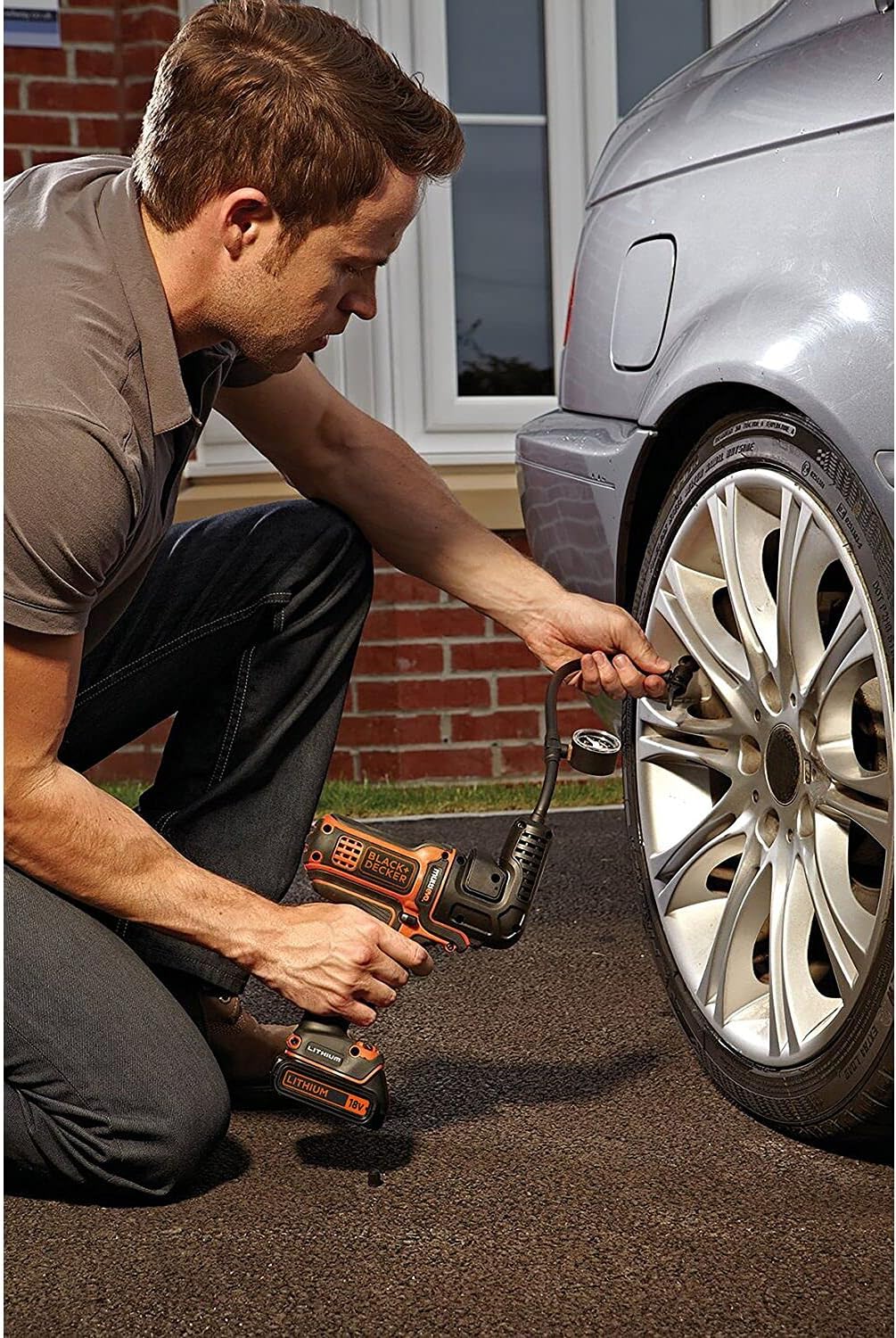 A person using the BLACK+DECKER Multievo Multi-tool Inflator Attachment to inflate a car tire.