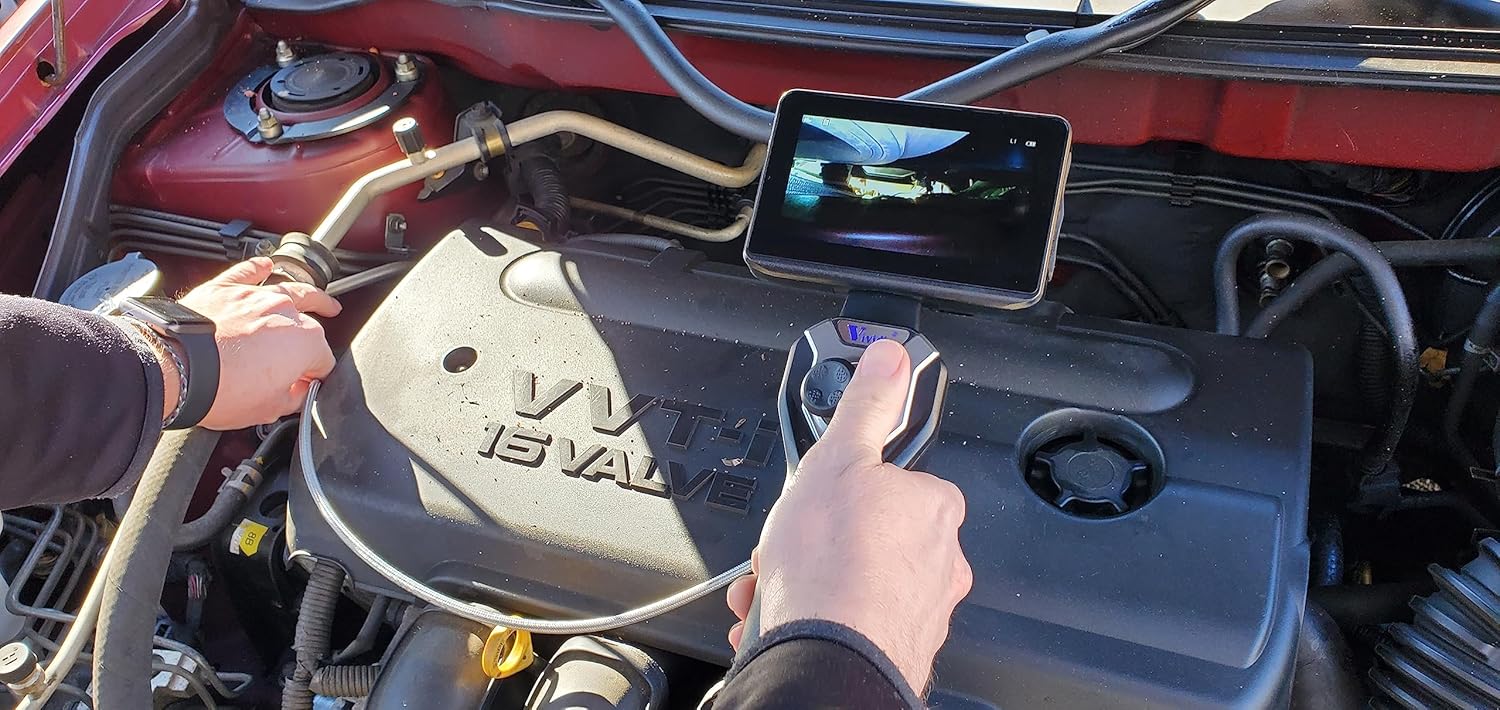 Person operating the borescope, adjusting the joystick while inspecting an engine bay