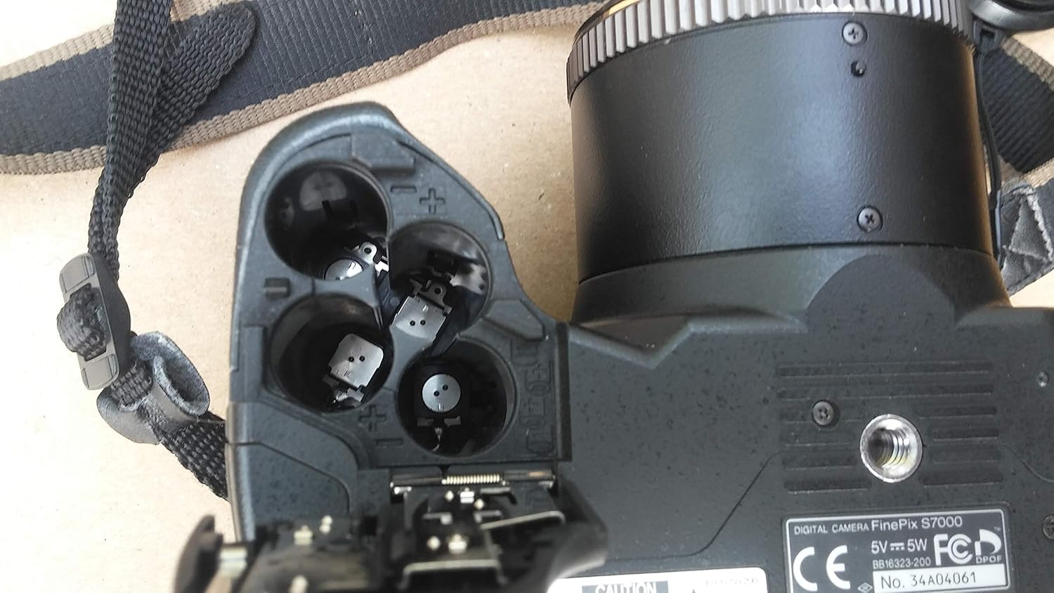 Open battery compartment of Fujifilm FinePix S7000 camera showing slots for four AA batteries.