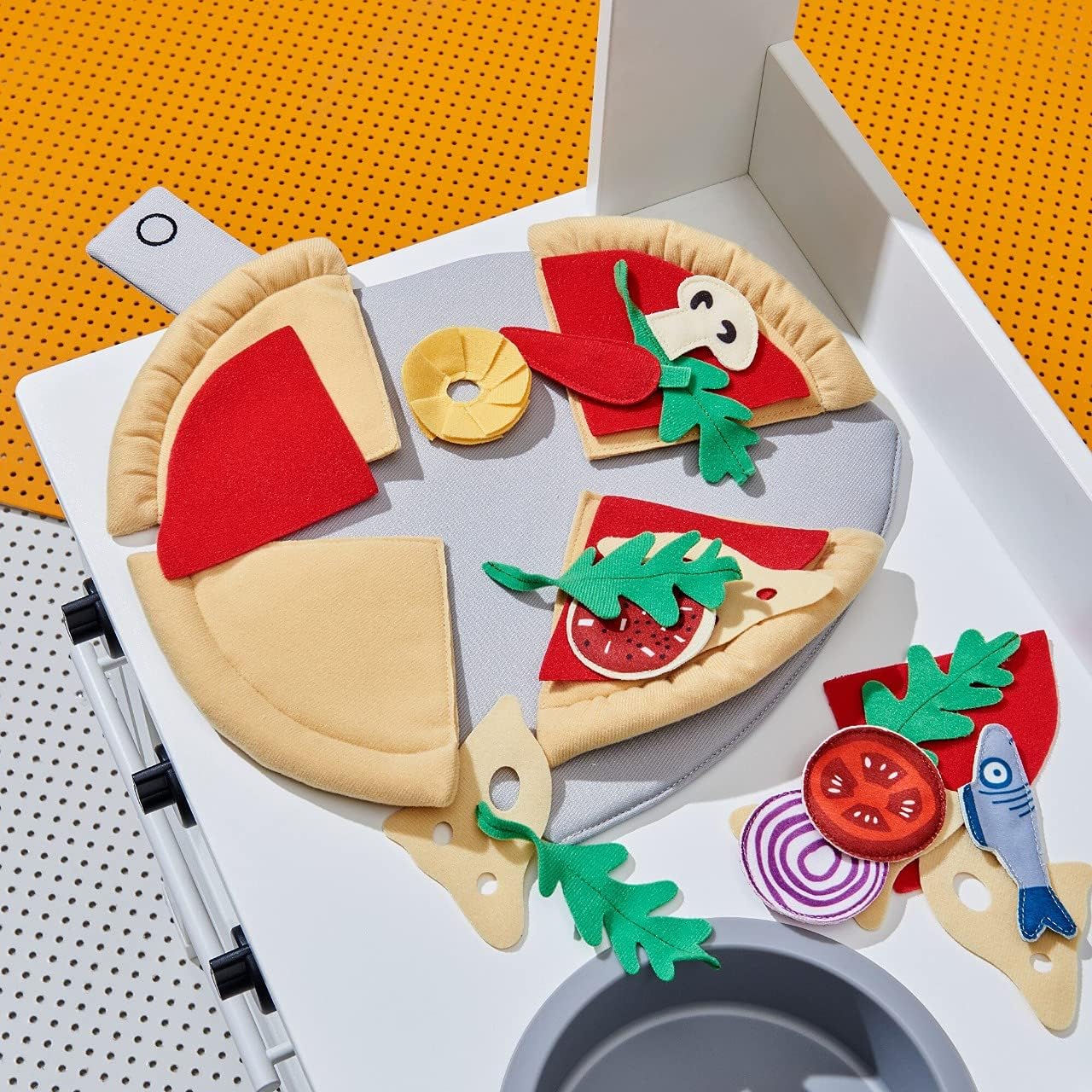 Close-up of felt pizza slices with various toppings being added