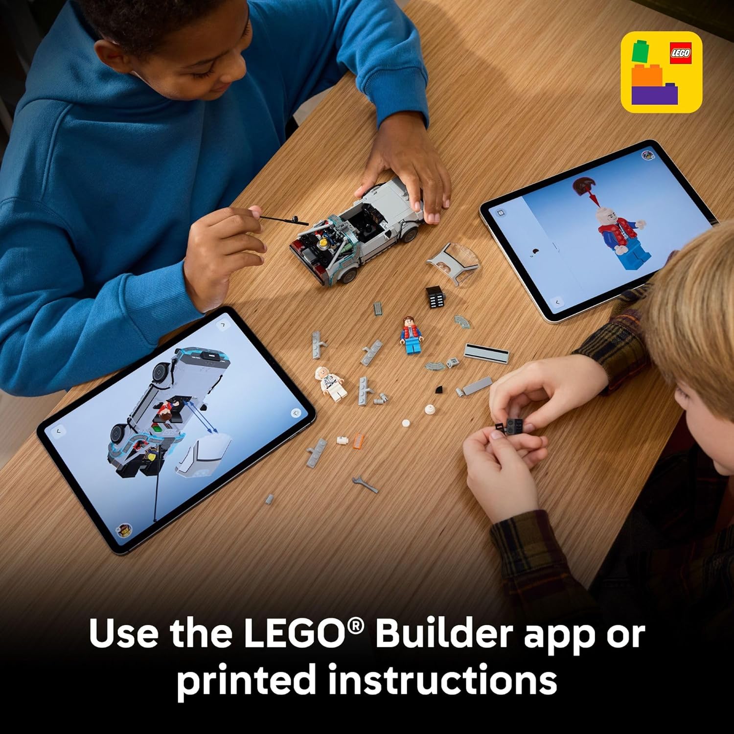Two children building the LEGO DeLorean, one following digital instructions on a tablet, the other assembling pieces.