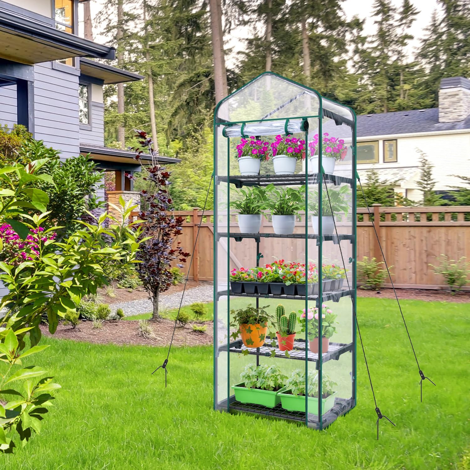 Ohuhu Mini Greenhouse placed outdoors in a backyard setting, filled with various potted plants.