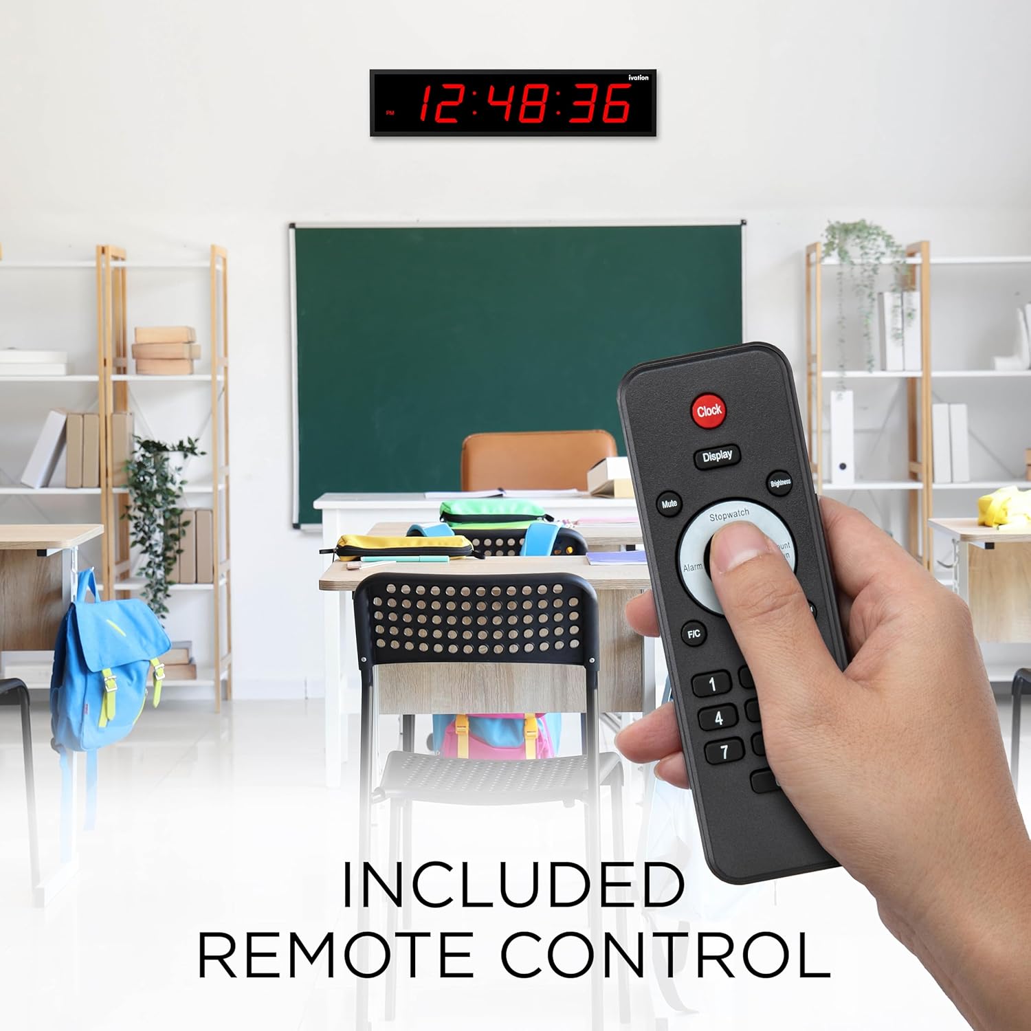 A hand holding the Ivation Digital LED Clock remote control in a classroom setting.