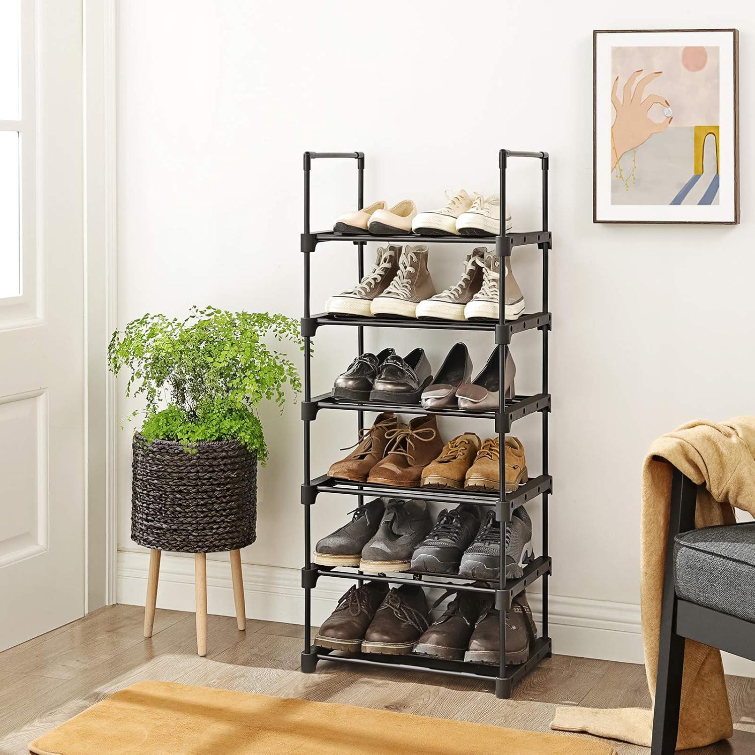The full 6-tier shoe rack placed in a living room or bedroom, holding various types of shoes and a plant on top.