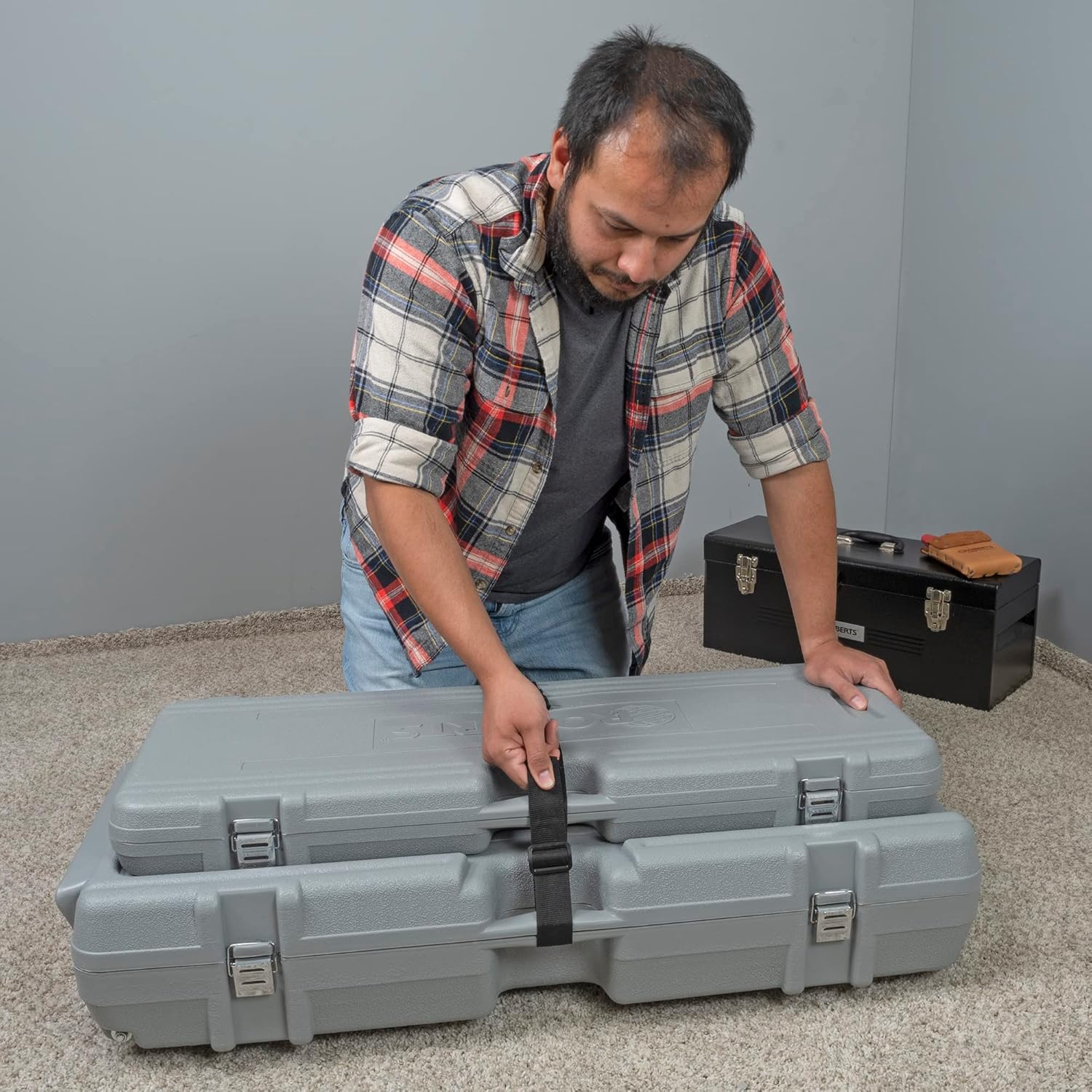 Man opening the carrying case for the carpet stretcher