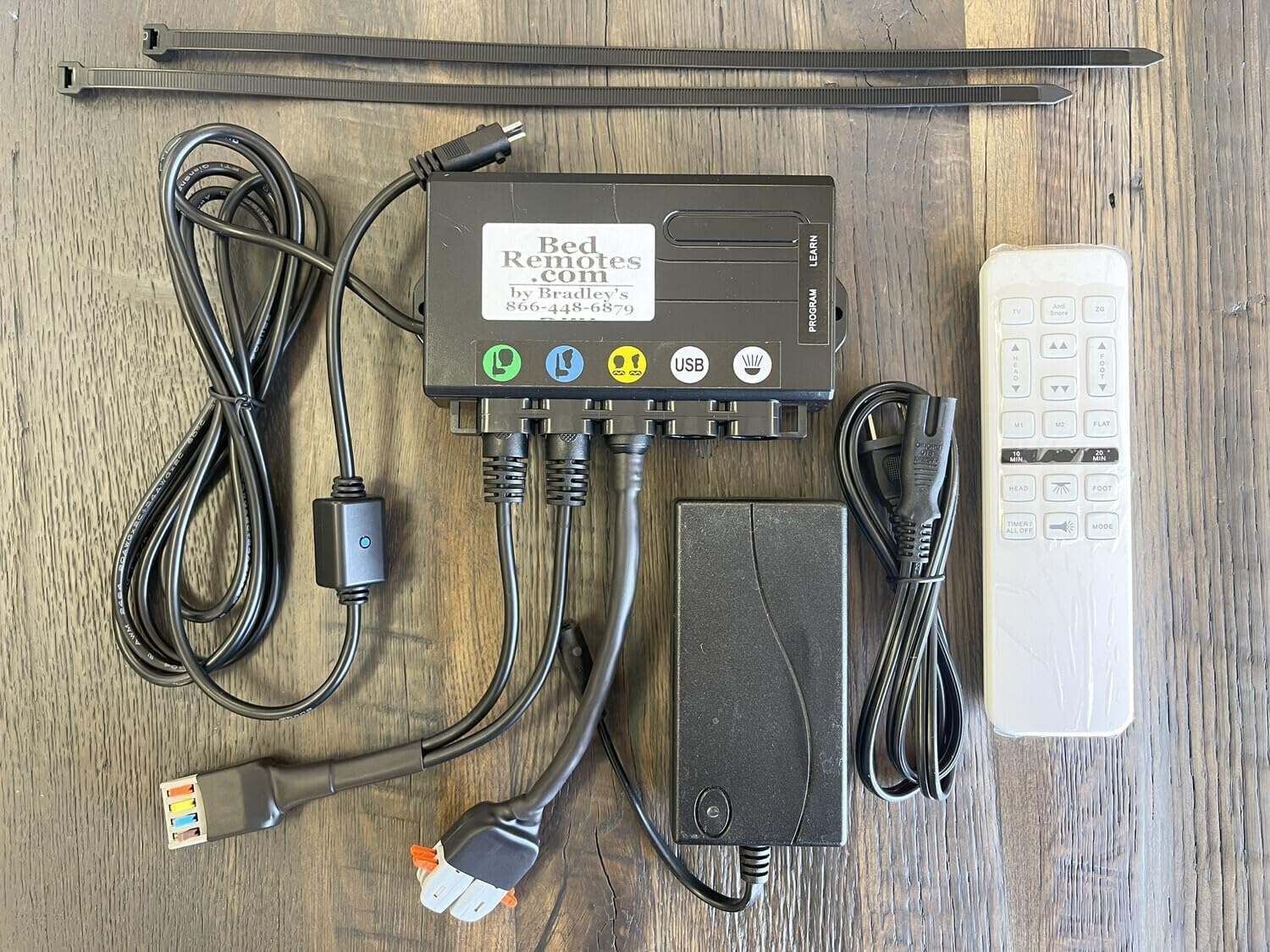 Image showing all components of the conversion kit laid out on a wooden surface, including the new control box, power supply, cables, and the new white remote.