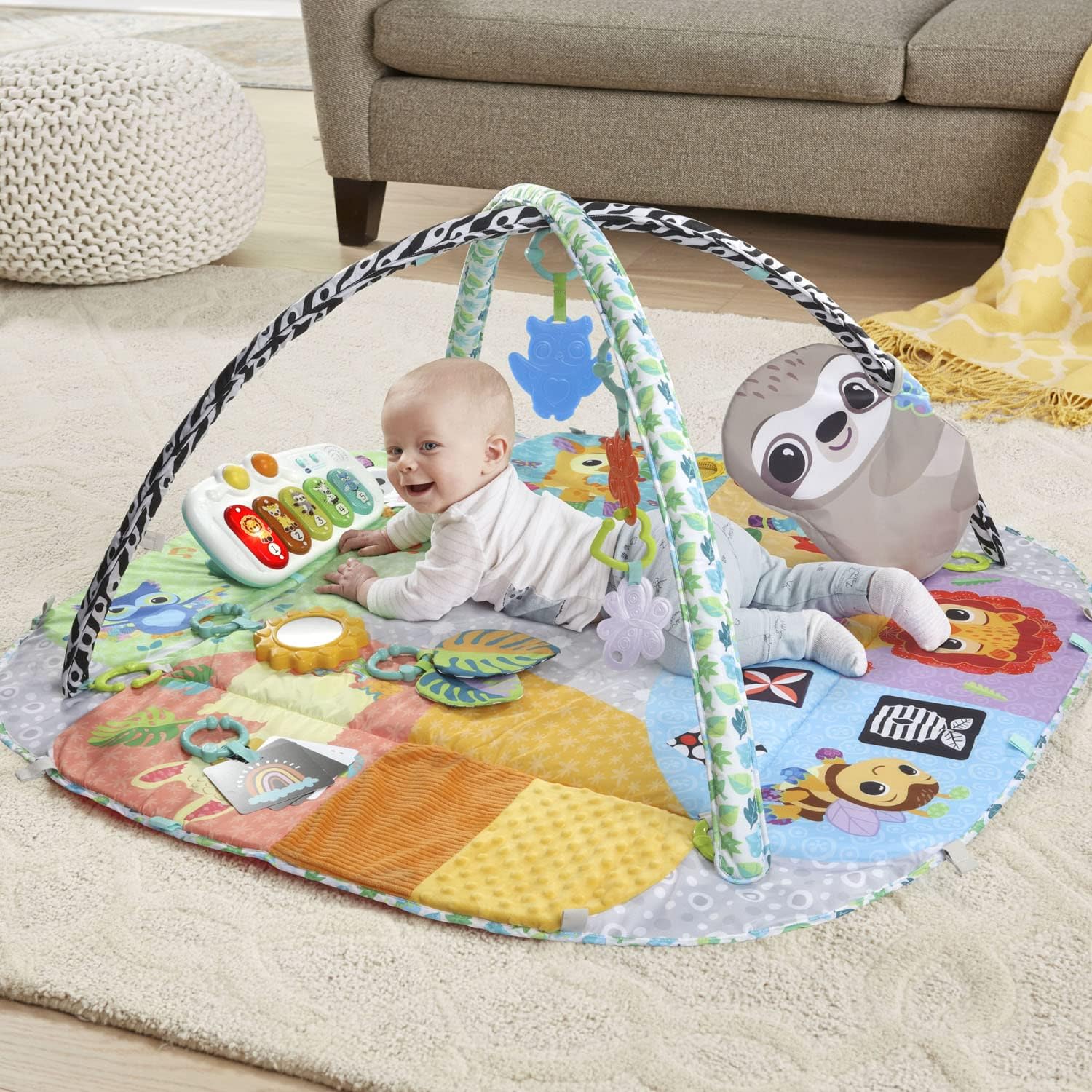Baby lying on the VTech 7-in-1 Senses and Stages Developmental Gym with arches and hanging toys