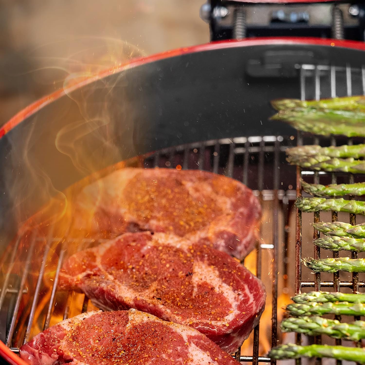 Steaks and asparagus grilling on the Kamado Joe Kettle Joe.
