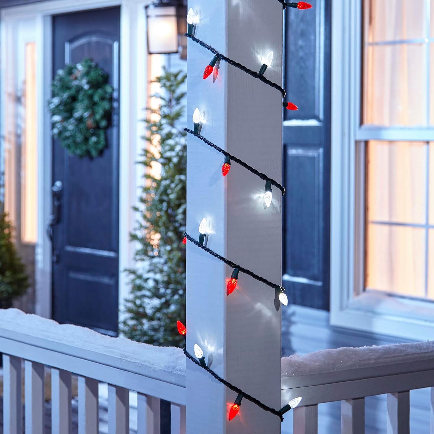 NOMA C6 LED Christmas Lights wrapped around an outdoor porch pillar, with a decorated front door in the background.