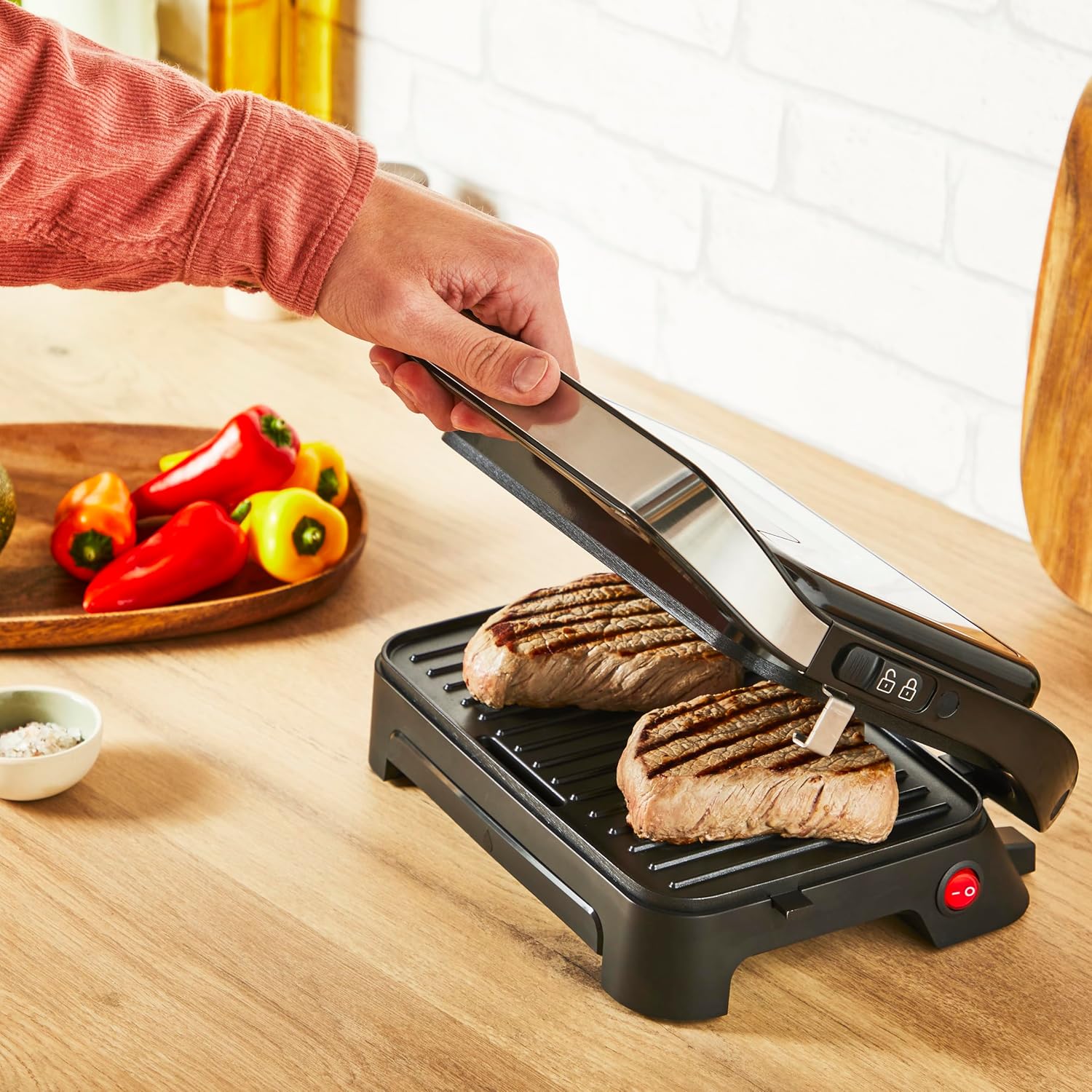 Person grilling two pieces of meat on the Tefal Inicio Compact grill.
