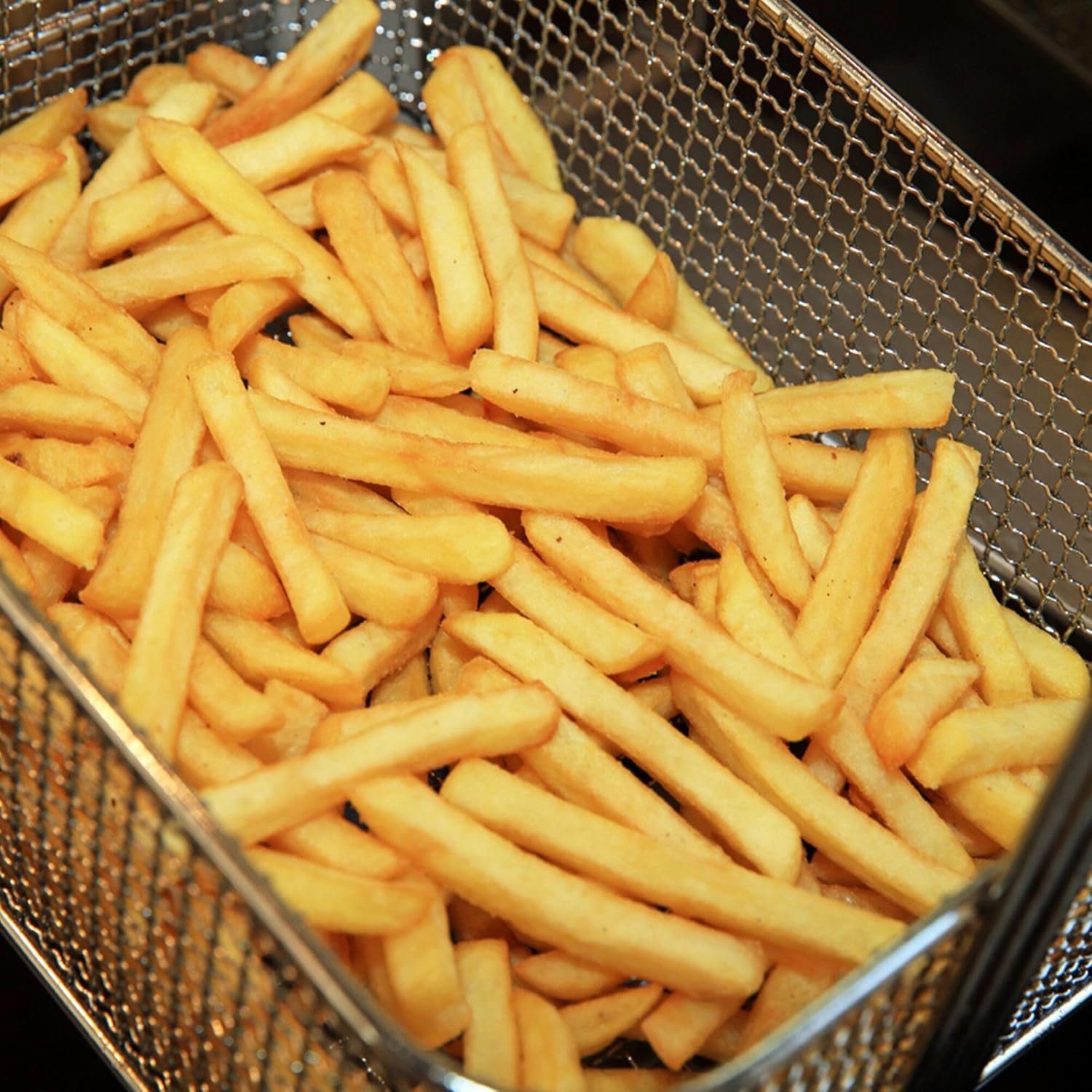 Close-up of golden french fries in a frying basket