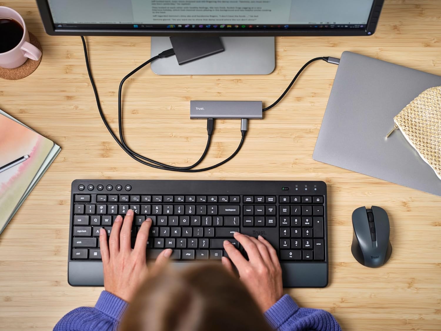 ค่าใช้จ่ายเหนือศีรษะ view of a desk setup with a laptop, monitor, keyboard, mouse, and the Trust Halyx USB-C Hub connected