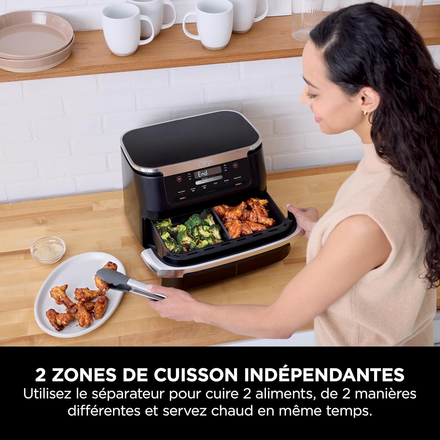 A person using the Ninja FlexDrawer Air Fryer with the separator in place, cooking chicken wings in one zone and broccoli in the other.
