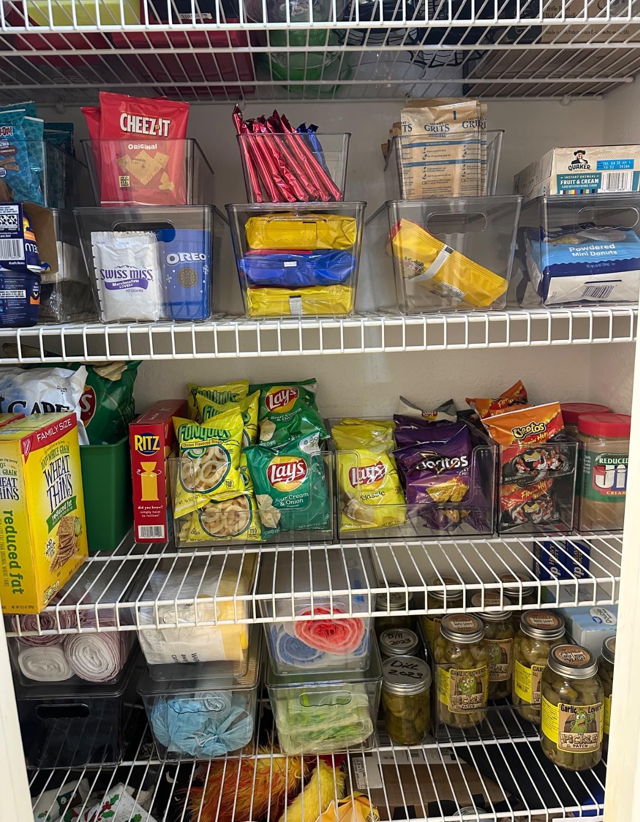 Pantry shelf organized with clear stackable snack bins