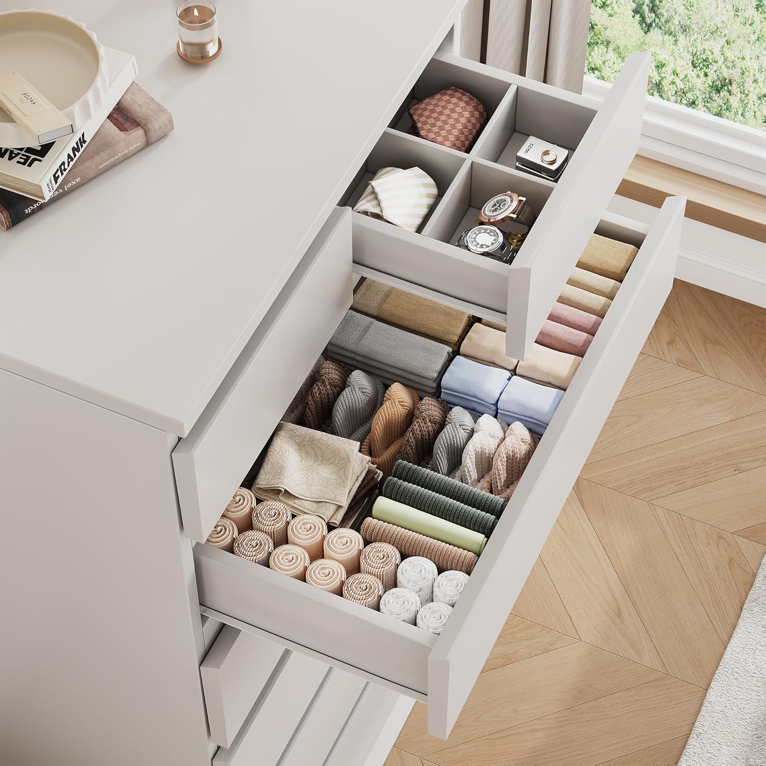 An open dresser drawer filled with neatly folded clothes and a top drawer with a jewelry organizer insert.