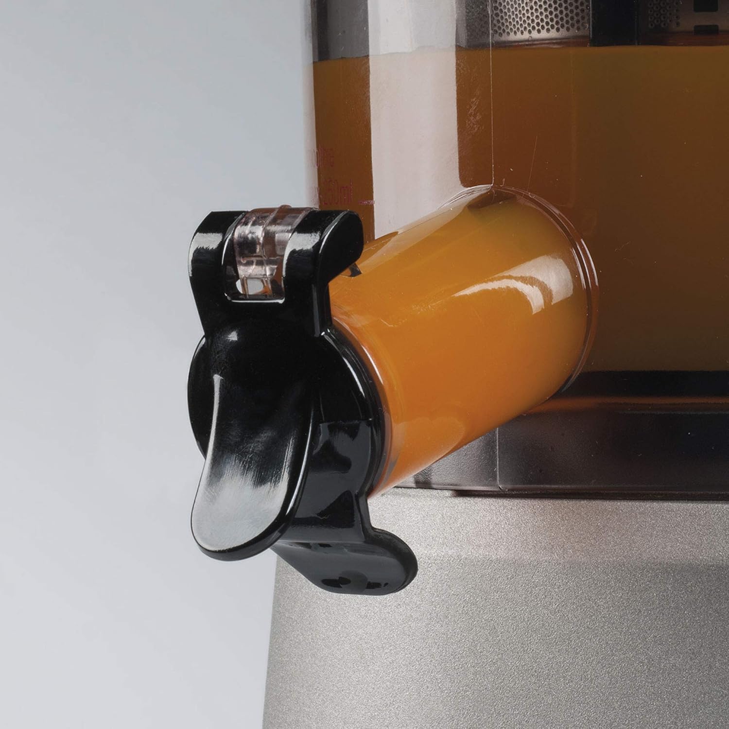 Close-up of the juice spout with cap open, dispensing juice.