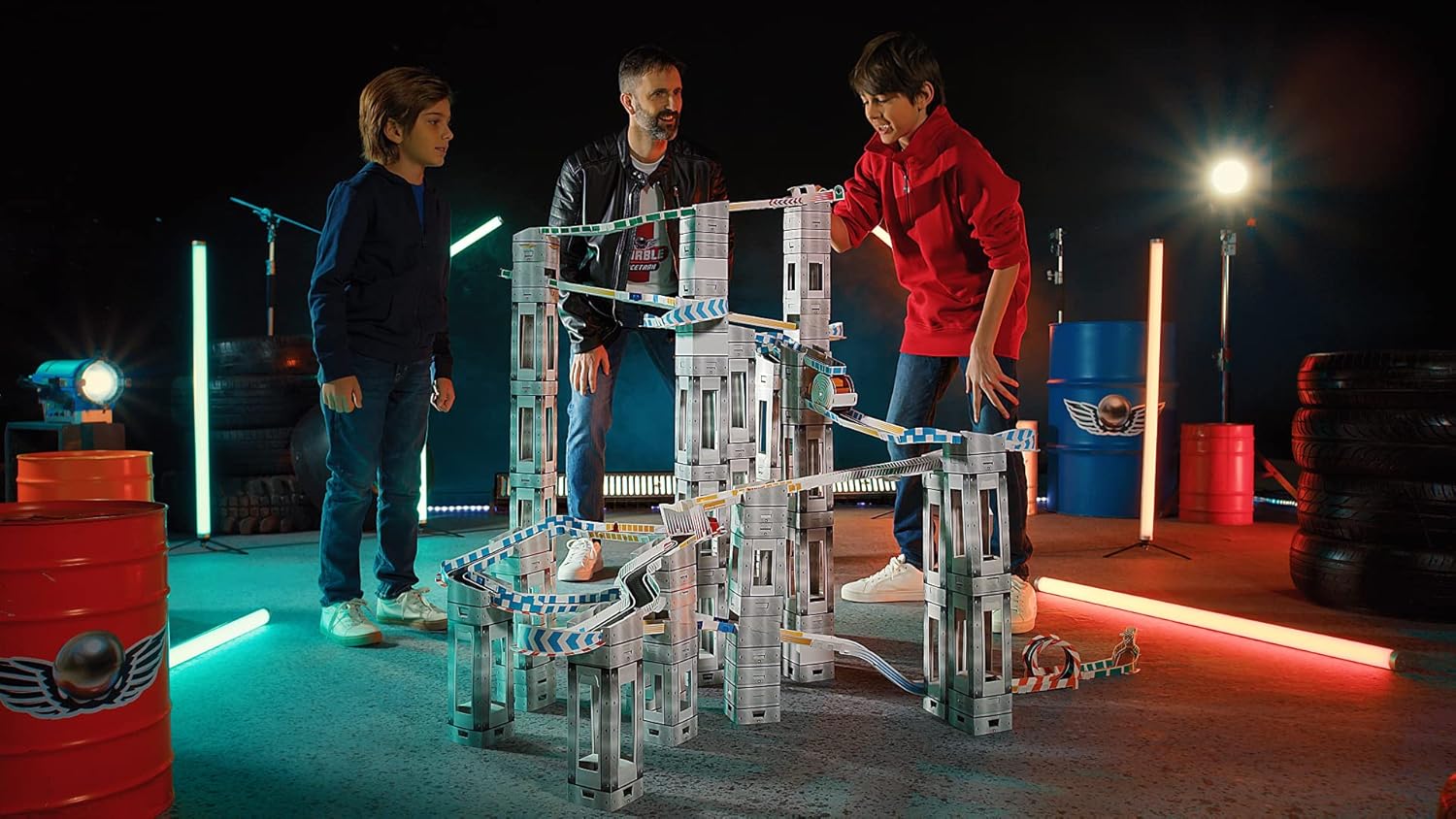 Two children and an adult observing the assembled marble run