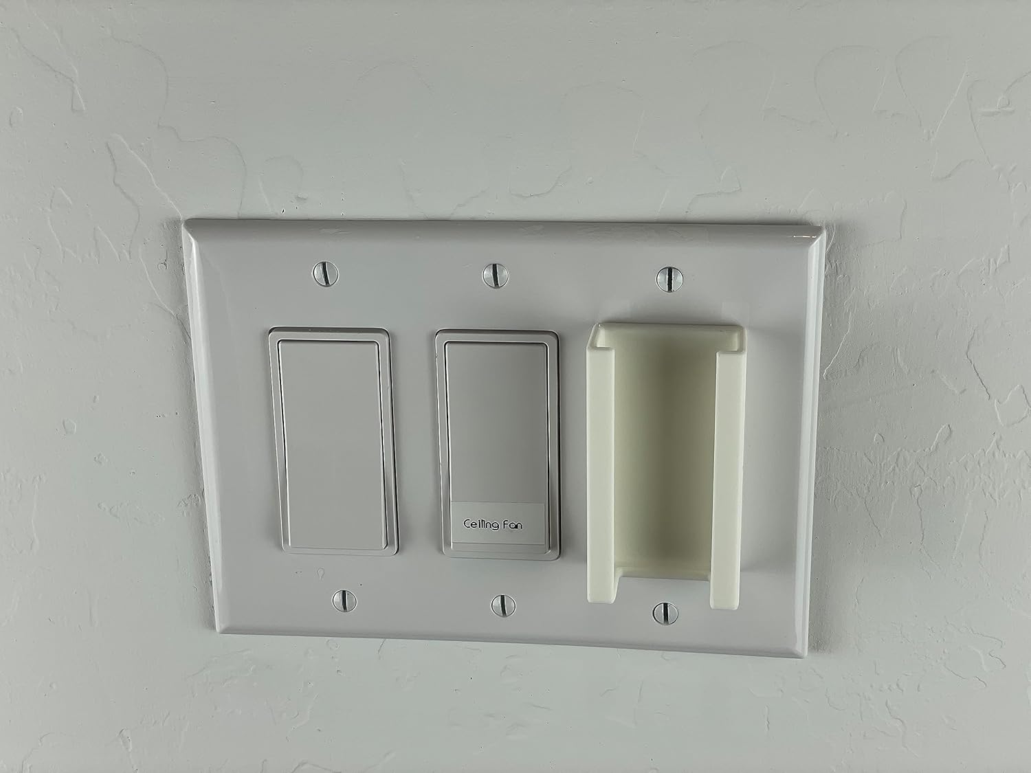 The white remote mount fully inserted into a wall switch plate, showing a seamless fit.