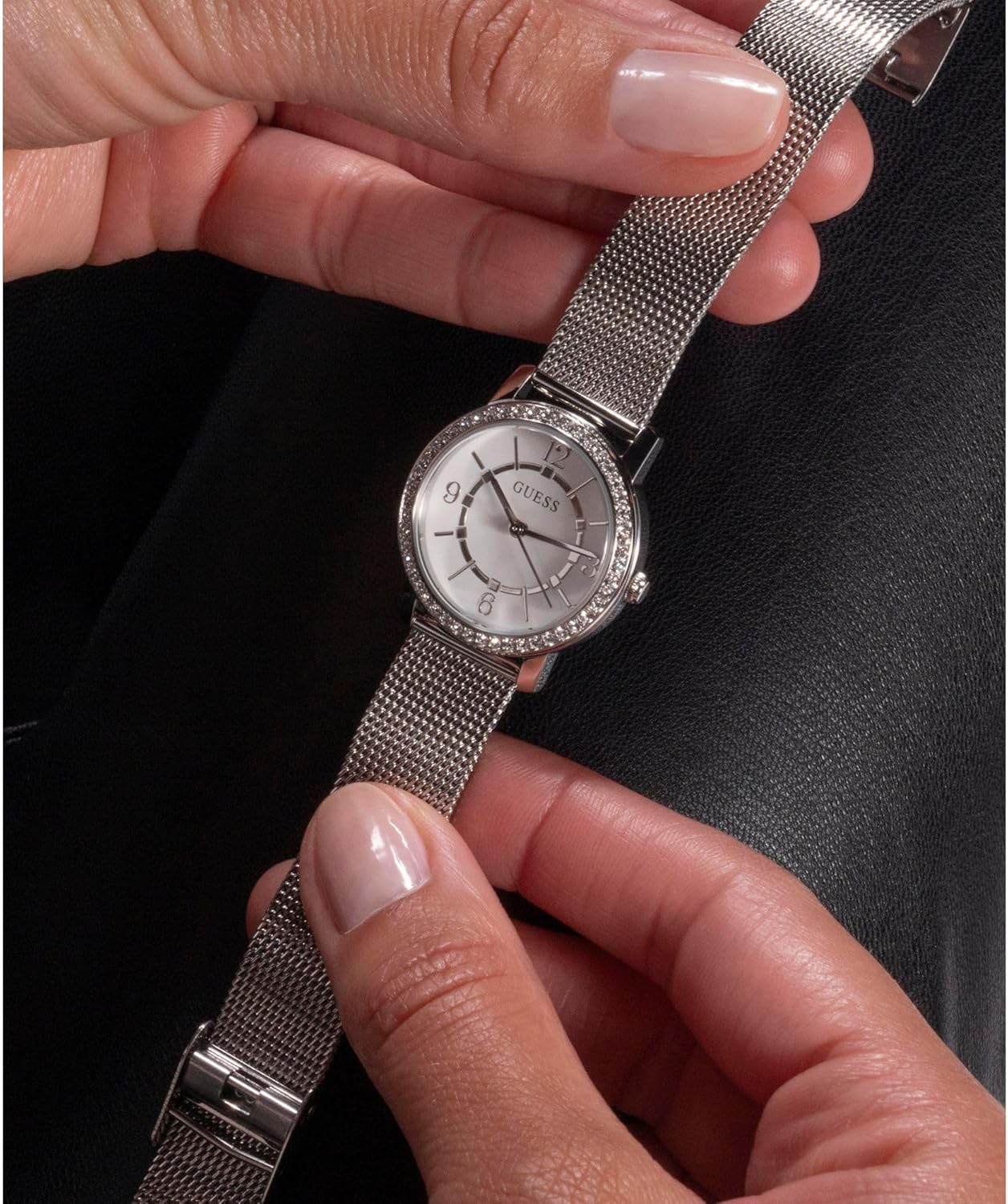 Hands adjusting the mesh strap of the GUESS Ladies 28mm Watch.