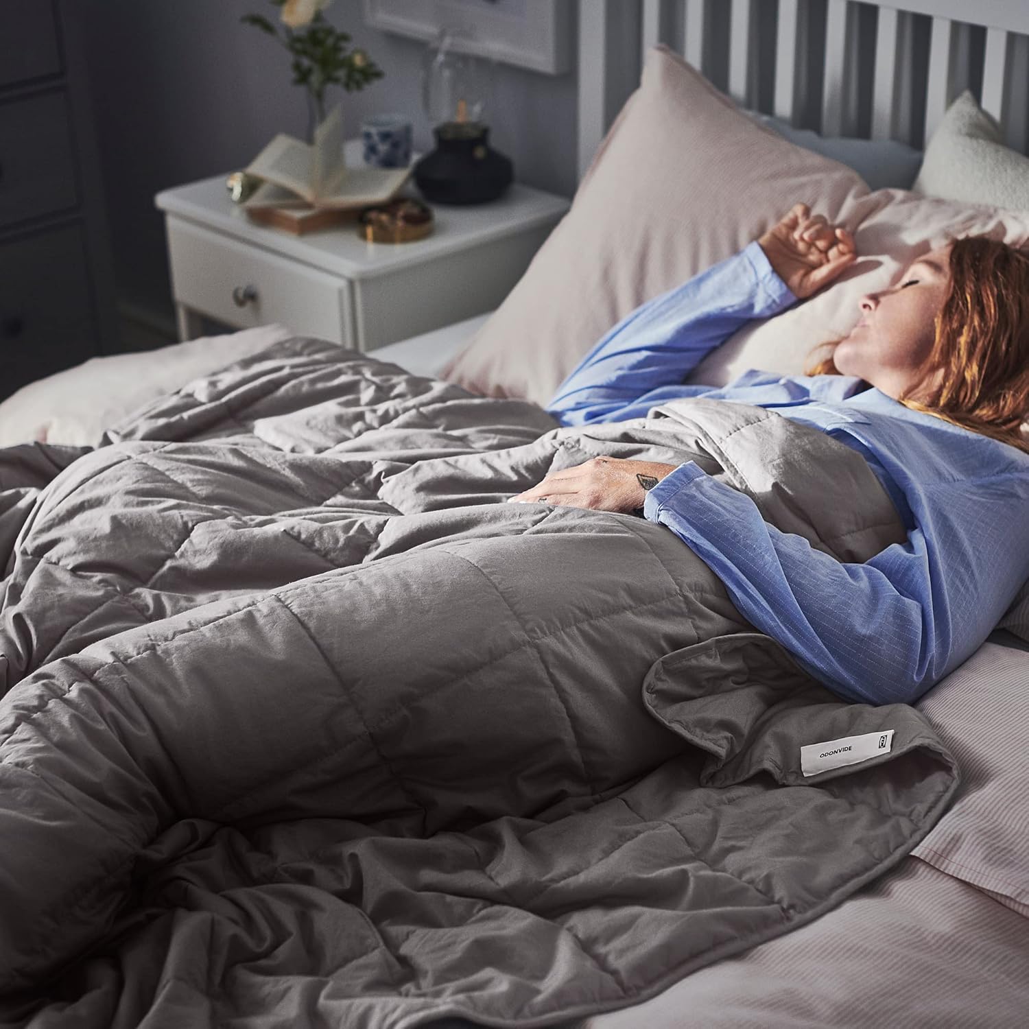 A person sleeping peacefully in bed, covered by the IKEA ODONVIDE weighted blanket.