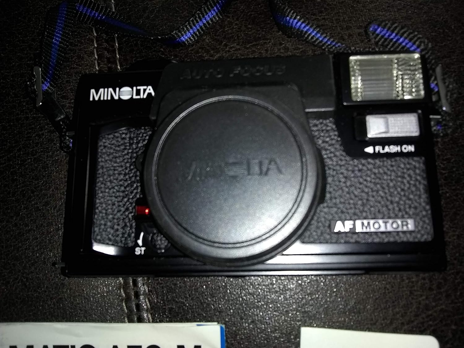 Top view of Minolta Hi-matic AF2-M camera with lens cap, showing flash unit and autofocus label.