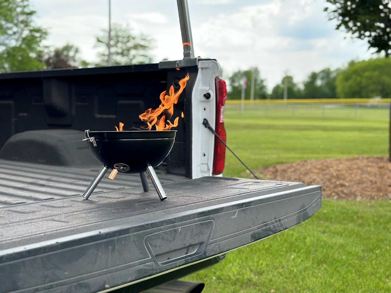 Freedom Stove BallBQ Grill placed in the bed of a pickup truck, demonstrating portability and secure latching