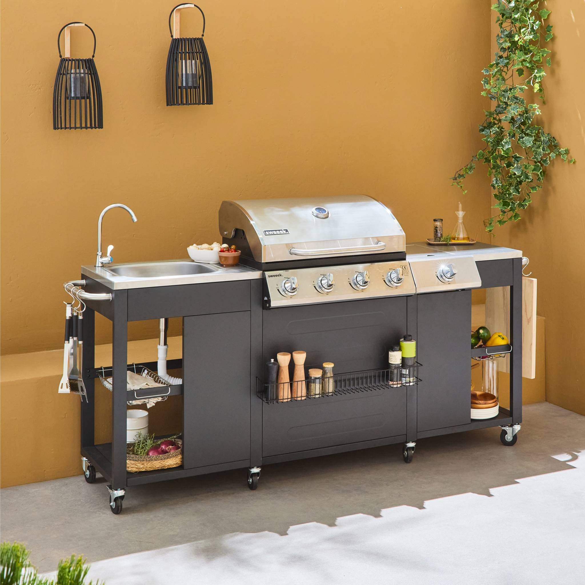 Alice's Garden - Barbecue. cuisine extérieure gaz - D'Artagnan - Barbecue 5 brûleurs dont 1 feu latéral. inox et noir. évier. planche à découper bois. ustensiles