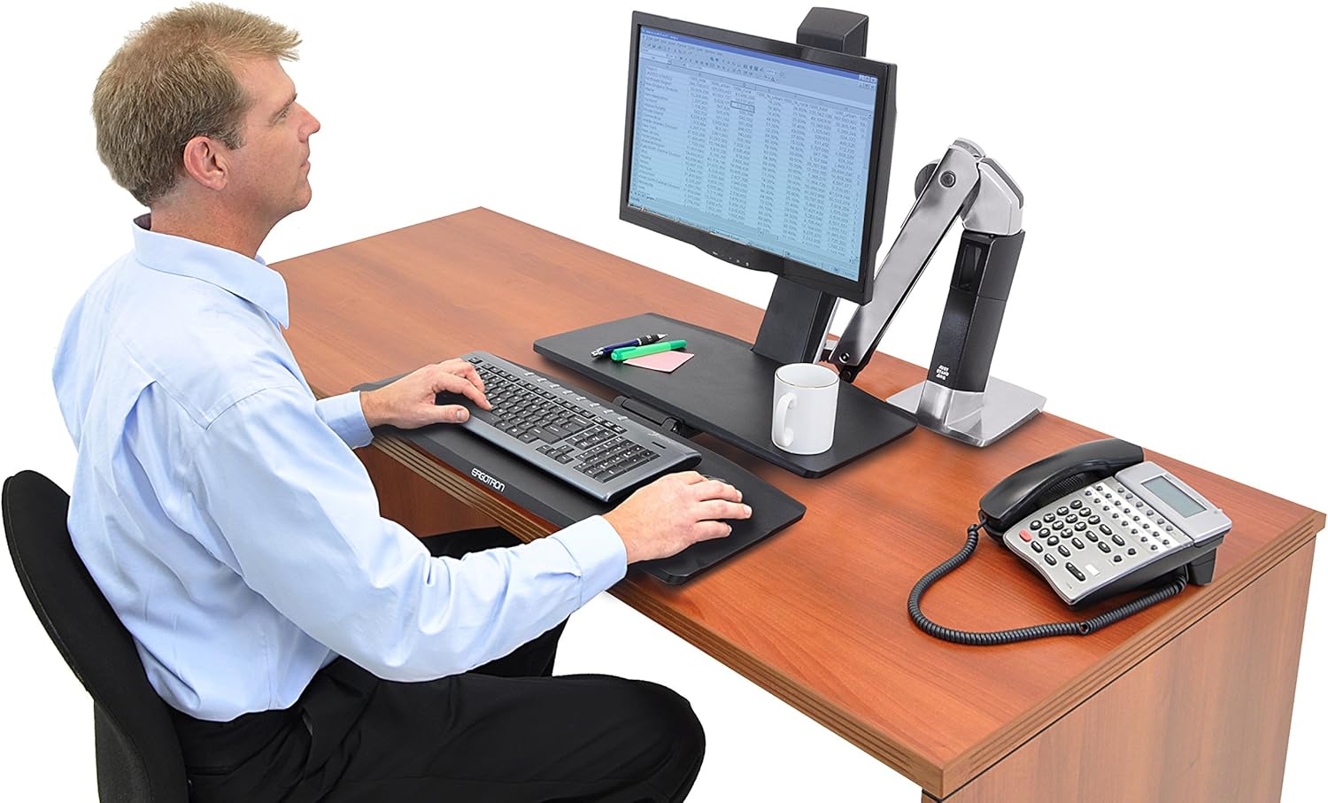 Man sitting and working at a desk using the Ergotron 24-314-026 sit-stand workstation.