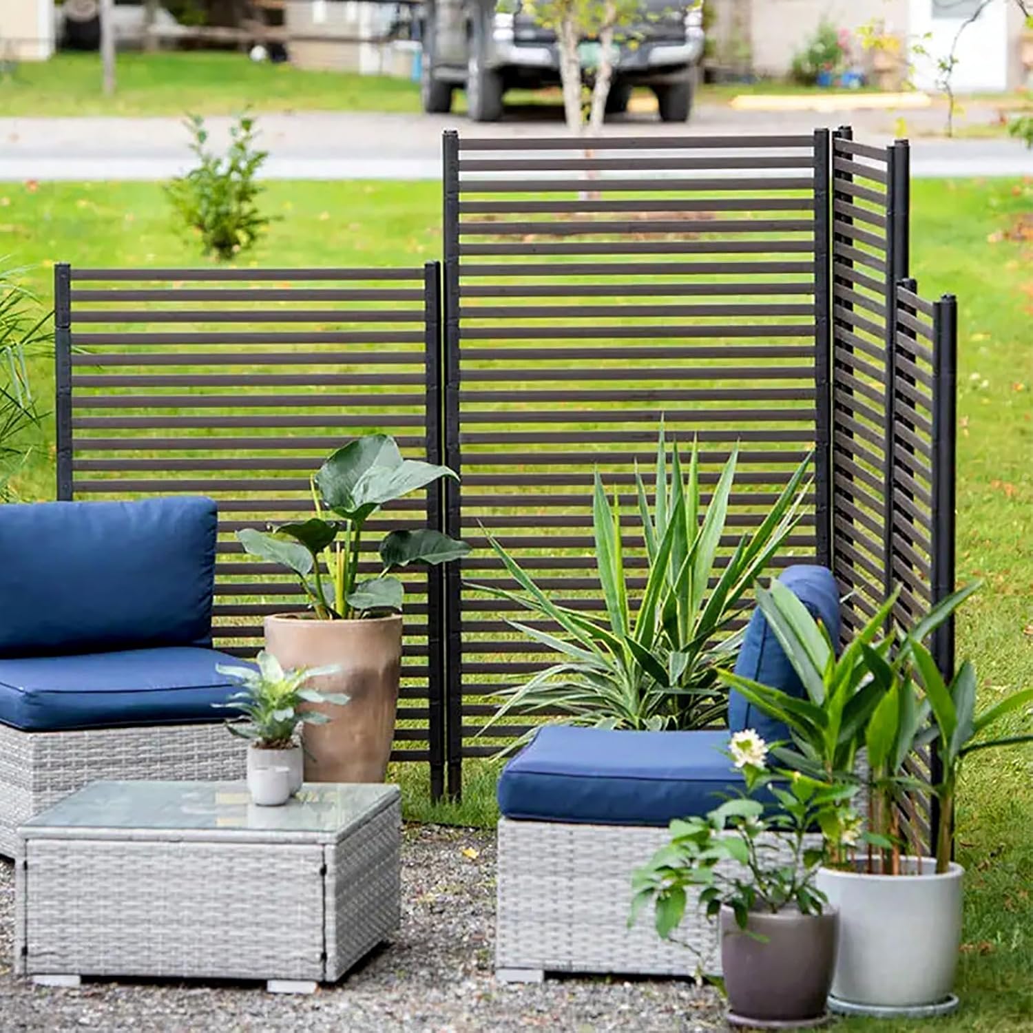 Multiple privacy screens arranged in an outdoor garden setting with patio furniture, providing visual separation and aesthetic appeal.