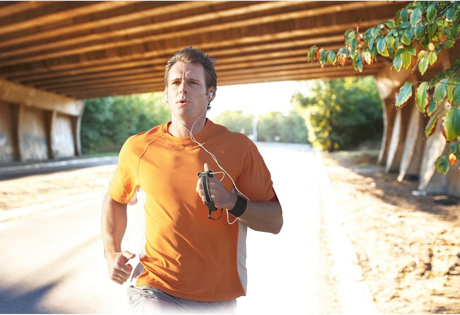 Man running outdoors wearing the cellularline Sport Handband on his arm