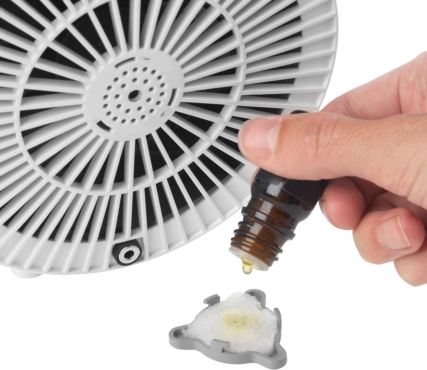 Hand adding essential oil drops to an aroma diffuser pad for the Beldray Arctic Dome.