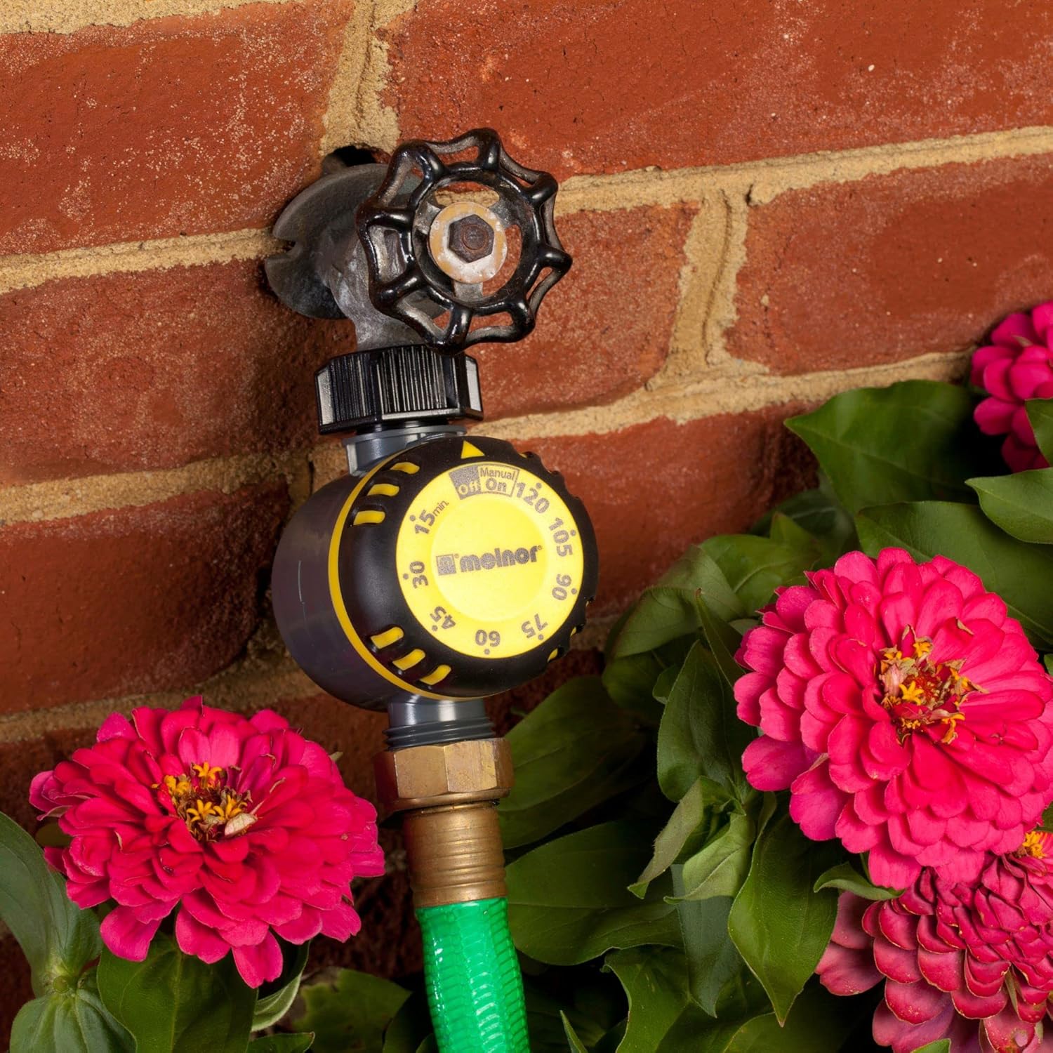 Melnor Mechanical Timer connected to an outdoor faucet with a green hose.