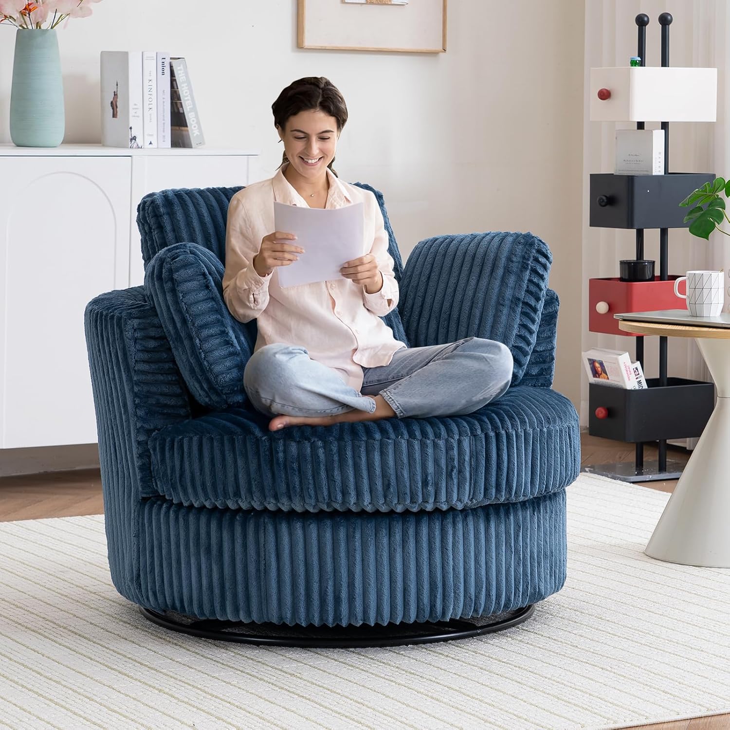 A person comfortably seated in the blue swivel barrel chair, reading a document