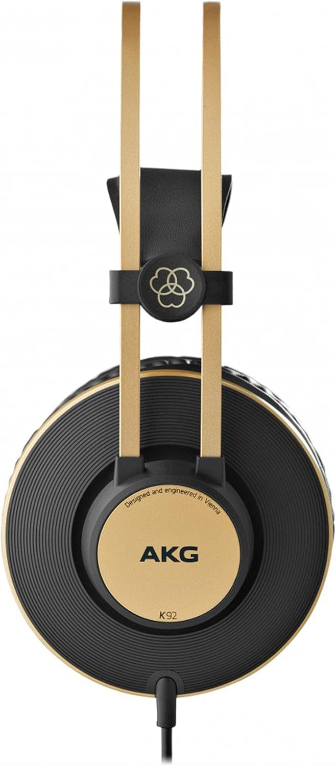 Vista frontal do fone AKG K92 mostrando uma das conchas com o logo AKG, detalhes dourados, arco duplo dourado e almofada preta ao fundo, sobre fundo branco.