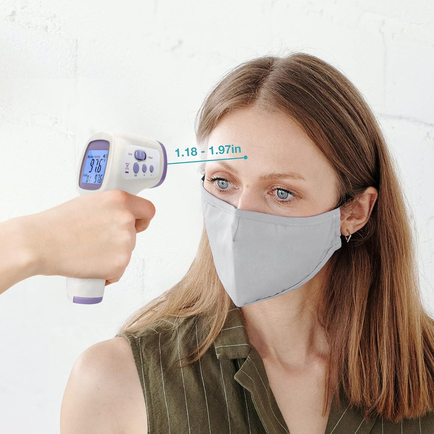 Person using the non-contact thermometer to measure forehead temperature, showing the recommended distance of 1.18 to 1.97 inches.