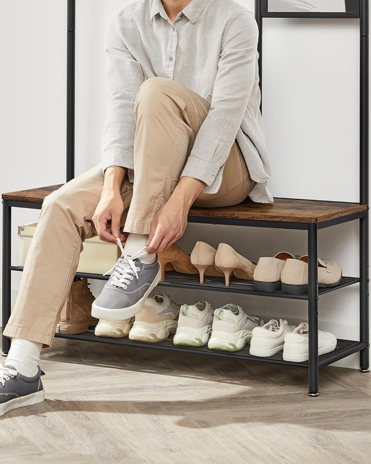 Person sitting on the hall tree bench to tie shoes