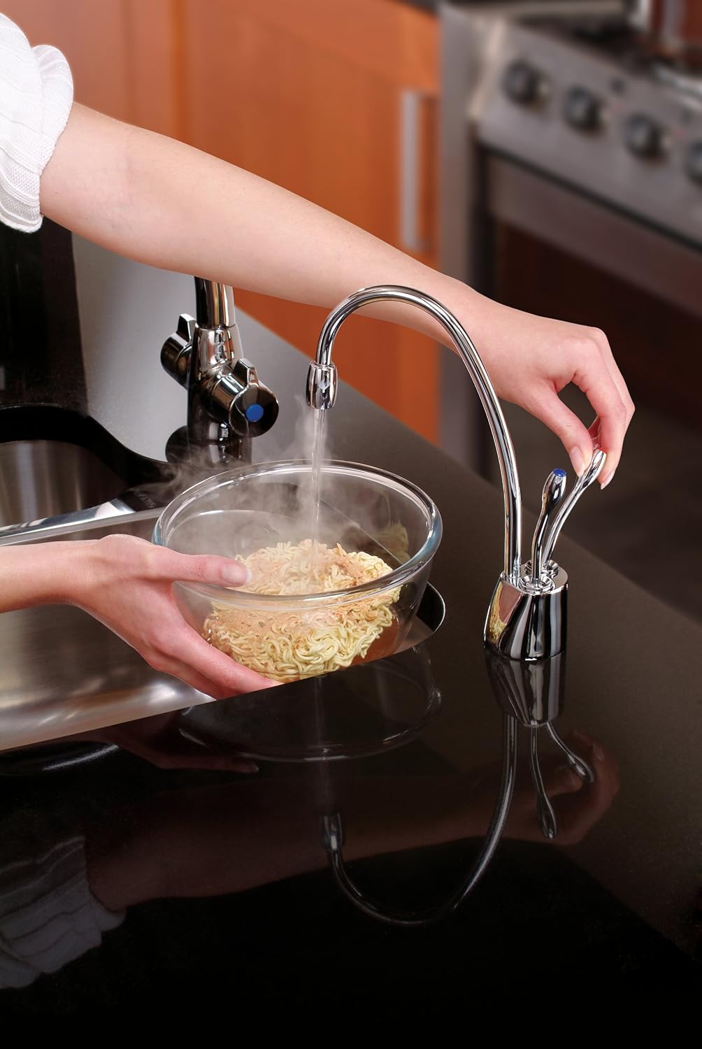 Hand operating the hot water lever on the InSinkErator faucet to fill a bowl with hot water