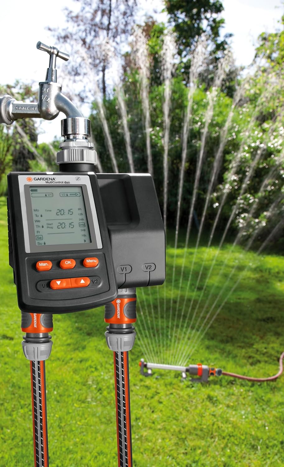 Gardena Multi-Control Duo Water Computer installed on a tap, with hoses connected to a sprinkler system actively watering a lawn.