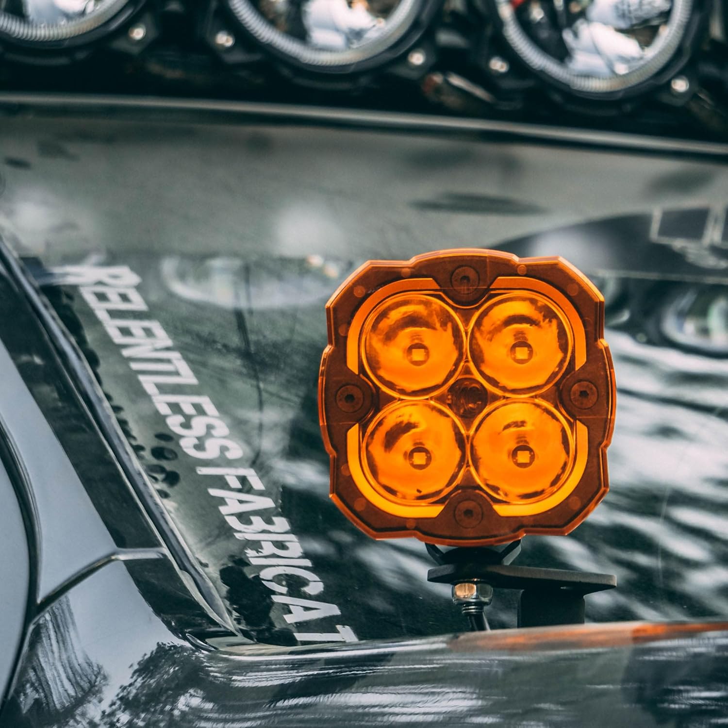 Close-up of a single KC Hilites Flex ERA 4 LED light pod with an amber lens, highlighting its customizable bezel and amber LED backlight.