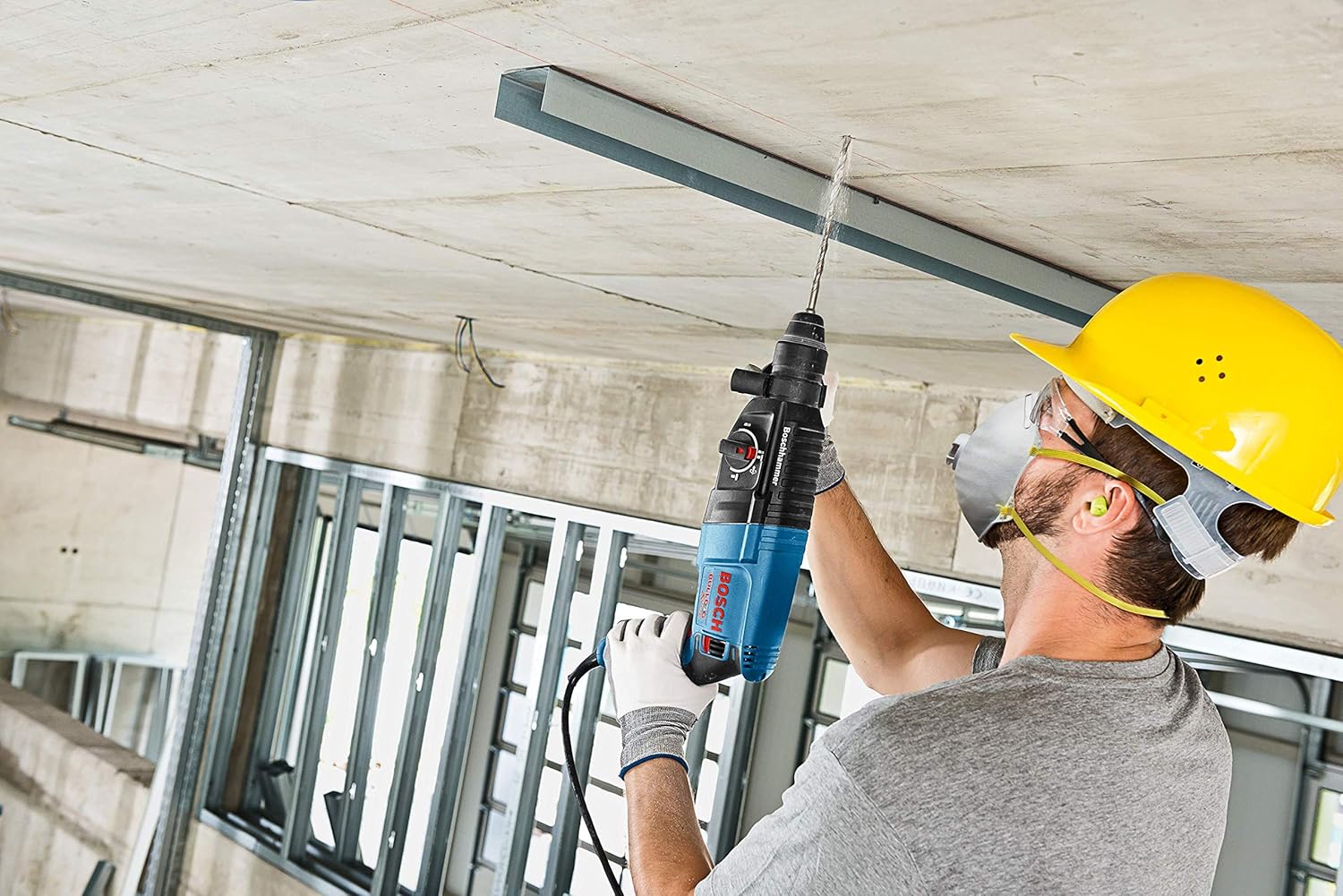 Worker drilling into a concrete ceiling with the rotary hammer