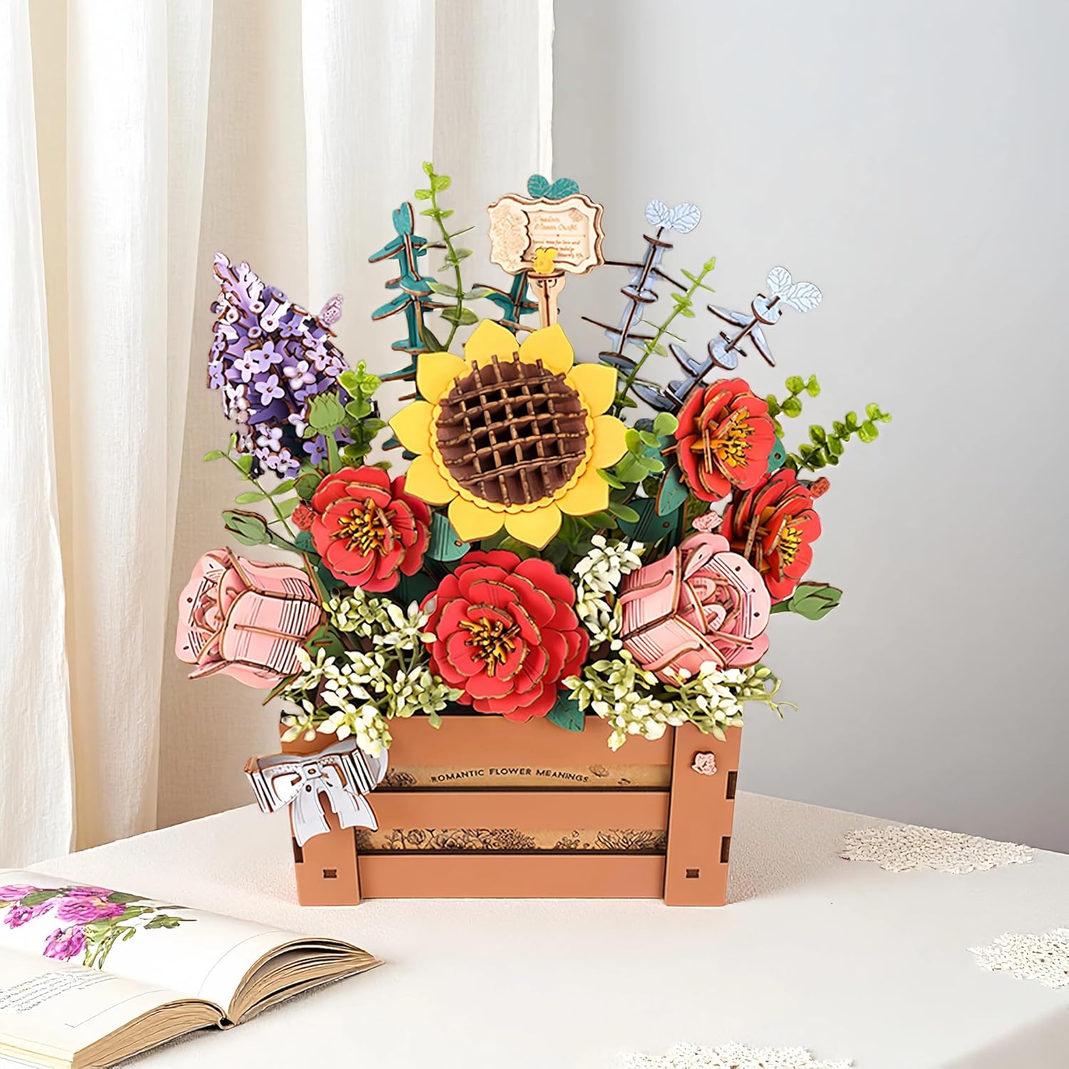 The fully assembled ROBOTIME 3D Wooden Bloom Box Puzzle, featuring a variety of colorful wooden flowers and greenery in a brown wooden box, displayed on a white table.